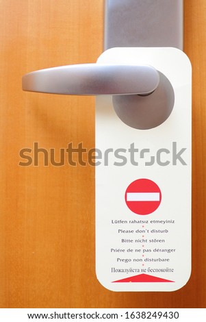Information flyer with text Please do not disturb in different languages. Wooden closed door at the hotel. Silence concept for relaxation
