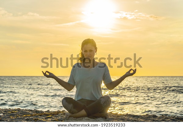 Information overload concept. Woman in the yoga pose
sitting on the street surrounded by fast passing cars. Street
noise, loud cars, and ambient noise. Noise pollution and inner
workings. 