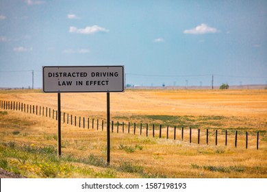 Information Road White Sign, Distracted Driving Law In Effect., On Canadian Rural Country Roadside, Against Yellow Prairies And Plains