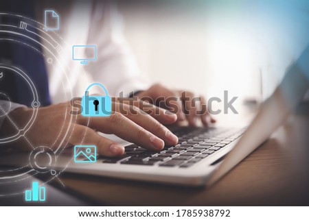 Information security. Young man using laptop at table indoors, closeup