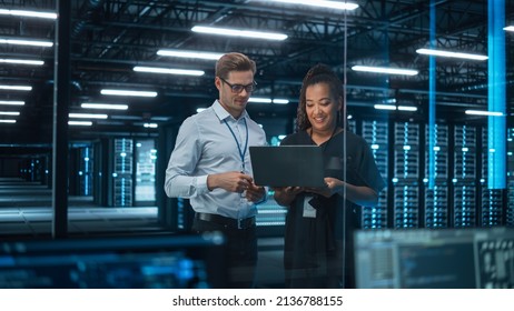 Information Technology Engineer and System Administrator Monitoring Web Services Cloud Solution Software and Sharing Ideas with Each Other in Big Data Center Server. People Use Laptop. - Powered by Shutterstock