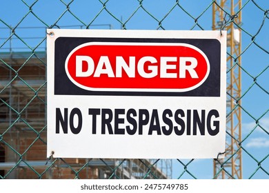 Information with warning sign and no trespassing signboard against a wire mesh of a construction site