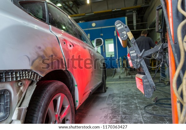 Infrared drying of car body parts\
after applying putty and paint on a white off-road vehicle in the\
body repair shop with red lanterns in the working\
environment