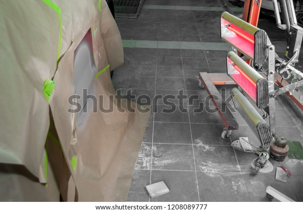 Infrared drying of car body parts\
after applying putty and paint on a red off-road vehicle in the\
body repair shop with red lanterns in the working\
environment