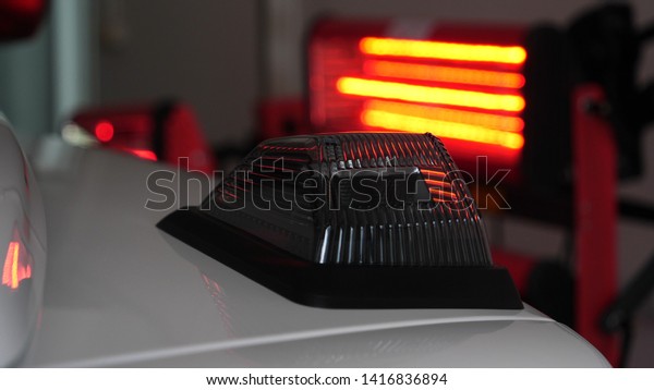 Infrared drying of car body parts after applying\
putty and paint on a white off-road vehicle in the body repair shop\
with red lanterns in the working environment. Concept of: Car\
Ceramic, Slow Motion.