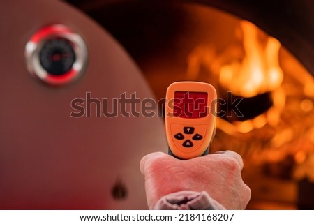 Infrared thermometer measuring temperature of wood fired pizza oven