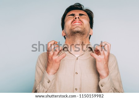 infuriated rage and anger. man went berserk with fury. portrait of a young brunet guy on light background. emotion facial expression. feelings and people reaction concept.