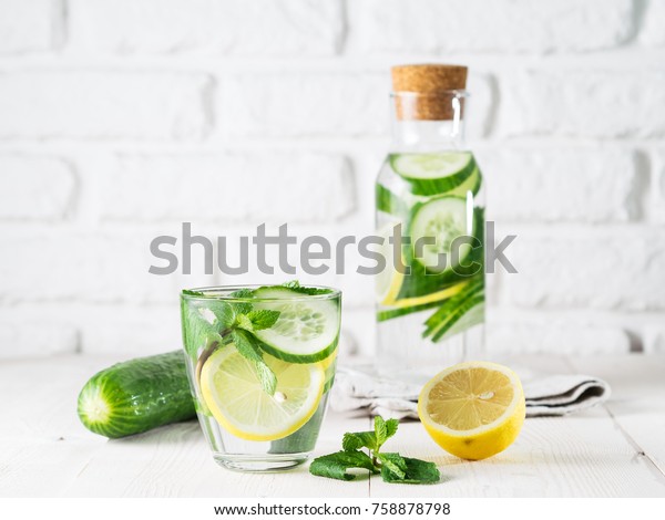 Infused detox water with cucumber, lemon and mint\
in glass and bottle on white table. Diet, healthy eating, weight\
loss concept. Copy\
space
