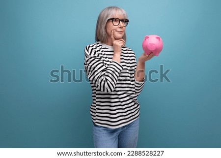 ingenious grandmother middle-aged woman has an idea where to invest her savings from a piggy bank on a bright background with save space