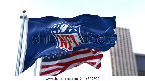 Inglewood, CA, USA, January 2022: The flag with\
the NFL logo waving in the wind with the US flag blurred in the\
background. The National Football League is a professional American\
football league