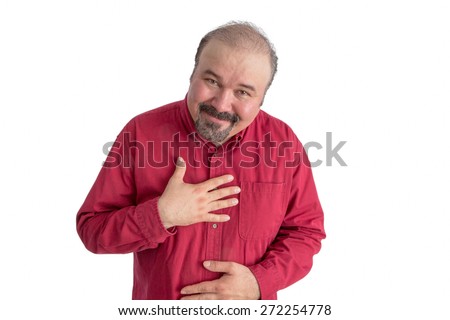 Ingratiating middle-aged balding man with a goatee showing his gratitude bending forwards with his hand to his heart and a pleased smile, isolated on white