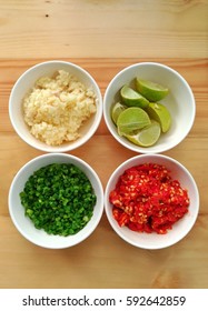 ingredient of food compose of chili, scallion, lime, garlic on the wood background in top view