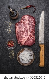 Ingredients For Cooking Beef Steak With Salt And Pepper  Carving Knife, Pepper Mill On A Dark Rustic Background Top View