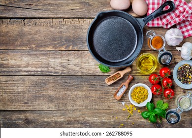  Ingredients for cooking and cast iron skillet on an old wooden table. Food background concept with copyspace