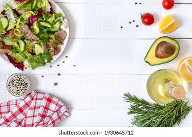 Ingredients For Cooking With Copy Space. Bowl Of Fresh Salad, Rosemary, Lemon, Spices And Oil On White Wooden Table. Food Background. Healthy Eating Concept.