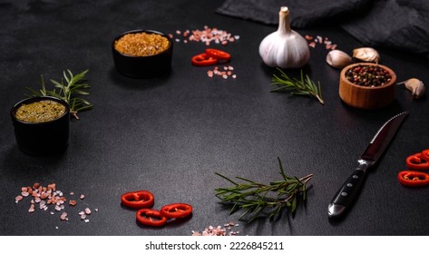 Ingredients for cooking at home: pepper, salt, rosemary, spices and herbs on a dark concrete background - Powered by Shutterstock