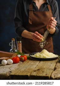 Ingredients For Cooking Pizza, Ravioli. Sauce, Salad. Chef Rubs Cheese On A Grater On A Wooden Table. Restaurant, Hotel, Food Blog, Instagram, Cookbook.