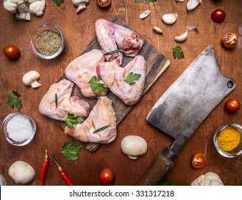 Ingredients for cooking Raw chicken wings with parsley and red pepper seasoning with mushrooms onions and salt and garlic on a cutting board  and meat cleaver on rusti? wooden background close up - Powered by Shutterstock