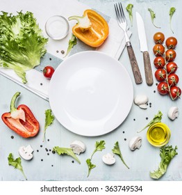 Ingredients for cooking salad cherry tomatoes, lettuce, peppers, spices and oil  laid out around a white plate on wooden rustic background top view close up - Powered by Shutterstock