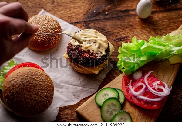 Ingredients\
for hamburger, cheeseburger. Wooden background. The hamburger is\
smeared with sauce. Cooking. Hamburger\
day.