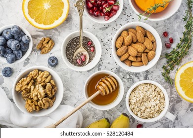 Ingredients for a healthy breakfast, nuts, oatmeal, honey, berries, fruits, blueberry, orange, pomegranate seeds, almonds, walnuts. The concept of natural organic food in season. Top view