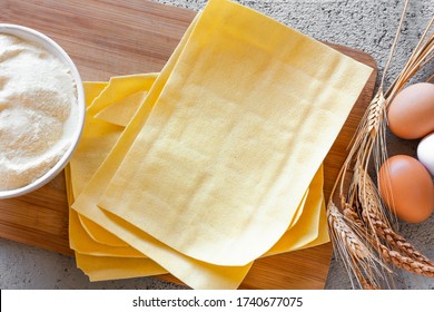 Ingredients for homemade lasagna. Rolling pin, flour, wheat ears, eggs and fresh lasagna sheets. Selective focus. Top view - Powered by Shutterstock