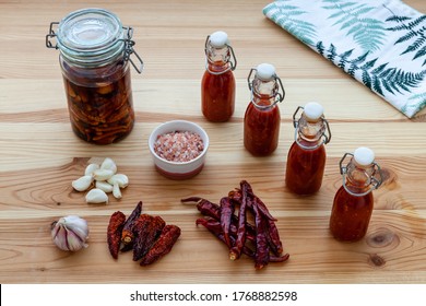 Ingredients And Hot Chili Sauce Made From Dried Fermented Chilies. Bottles, Jar, Bowl, Kitchen Towel And Dried Vegetables On Wooden Table. Homemade Cooking.