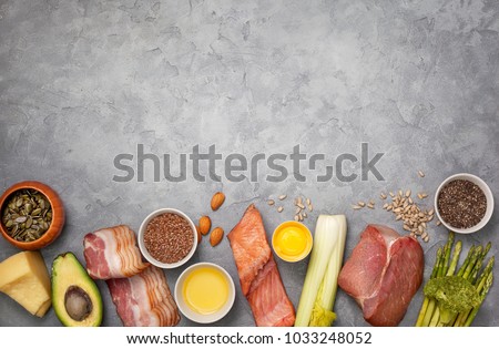Ingredients for ketogenic diet: meat, bacon, fish, broccoli, asparagus, avocado, mushrooms, cheese, sunflower seeds, chia seeds, pumpkin seeds, flax seeds. view from above. copy space