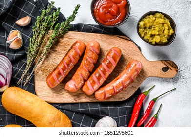 Ingredients for making homemade hot dogs. Sausages, fresh baked buns, mustard, ketchup, cucumbers. White background. Top view