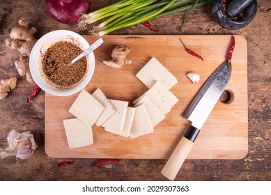 Ingredients For Making Hot Fried Tofu - Chunks Of Tofu, Sesame Seed Sauce, Hot Peppers, Onions, Garlic And Ginger On A Wooden Table