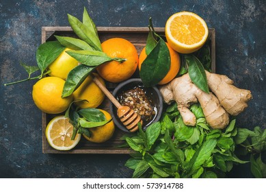 Ingredients for making immunity boosting natural drink. Lemons, oranges, mint, ginger, honey in wooden box over plywood background, top view. Clean eating, healthy lifestyle, detox, dieting concept - Shutterstock ID 573914788