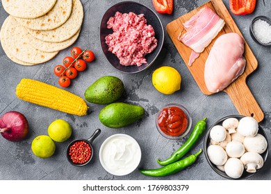 Ingredients for Mexican tacos with chicken and mice beef meat, corn herbs, salsa, over grey textured background, top view.