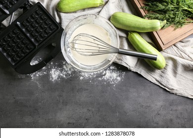 Ingredients and modern maker for preparing of squash waffles on grey table