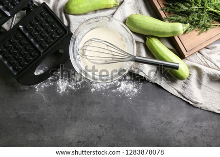 Ingredients and modern maker for preparing of squash waffles on grey table