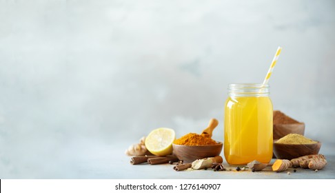 Ingredients for orange turmeric drink on grey concrete background. Lemon water with ginger, curcuma, black pepper. Vegan hot drink concept.