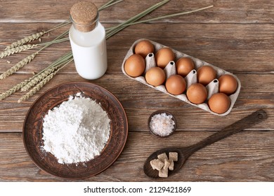Ingredients for pancake batter on dark wooden table - wheat flour, eggs, sugar, salt, milk Top view Selective focus.