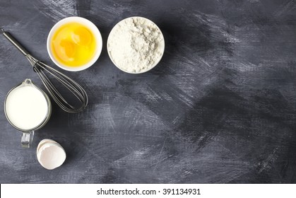Ingredients for pastries: flour, eggs, milk against a dark background