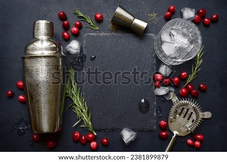 Ingredients and props for making festive christmas cocktail with cranberries and rosemary on a black slate, stone or concrete background. Top view with copy space.