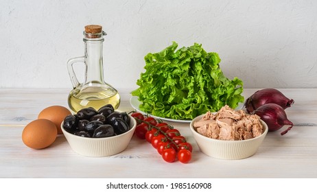 Ingredients For Tasty Tuna Salad: Canned Tuna Meat, Fresh Lettuce, Boiled Eggs, Cherry Tomatoes On The Vine, Black Olives, Red Onion And Olive Oil On The Table. Mediterranean Cuisine Recipe.