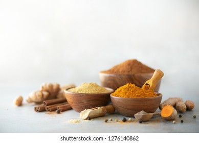 Ingredients for turmeric latte. Ground turmeric, curcuma root, cinnamon, ginger, black pepper on grey background. Spices for ayurvedic treatment. Alternative medicine concept. - Powered by Shutterstock