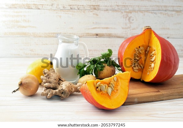 Ingredients for a warming autumn soup with red kuri
squash, coconut milk and ginger for Thanksgiving and Halloween,
white painted wooden background, copy space, selected focus, narrow
depth of field
