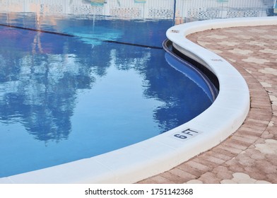 An Inground Swimming Pool With The Deck Undulating In An 