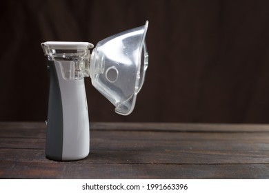 inhaler, white portable nebulizer on a wooden table.