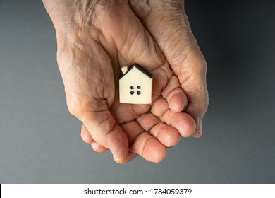Inheritance concept. Elderly woman hands holds a little toy house. Inherited property idea. - Shutterstock ID 1784059379