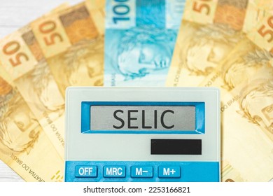 The initials SELIC referring to the basic interest rate in Brazil written on the display of a calculator with Brazilian Real banknotes in the composition. Brazilian economy and investments.
