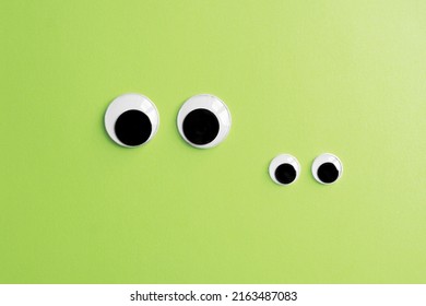 inivisible frog family - two pairs of googly eyes on green color paper background