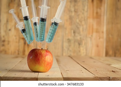 Injection into red apple -  Concept for Genetically modified fruit and syringe with colorful chemical GMO food