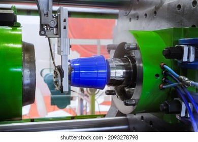 Injection Molding Machine With Robotic Arm During Work: Production Of Empty Polypropylene Blue Pots At Plastic Exhibition, Plant. Manufacturing, Recycling, Industry, Technology Concept