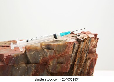 Injection Needle On Rock Reflects Solid Public Health Recommendations With Firm Data To Support Vaccine Guidance In Conceptual Image