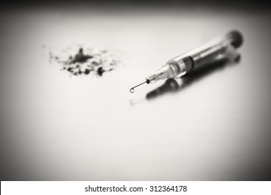 Injection Syringe, And In The Background A Pile Of White Flour. Images Of Drug Needles And Drug. The Picture Is Staged And There Is No Real Drugs. Image Includes A Platinum Effect.